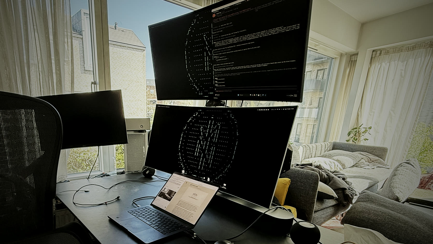 Copenhagen workstation in a lived-in room with stacked monitors, a laptop, and daylight windows